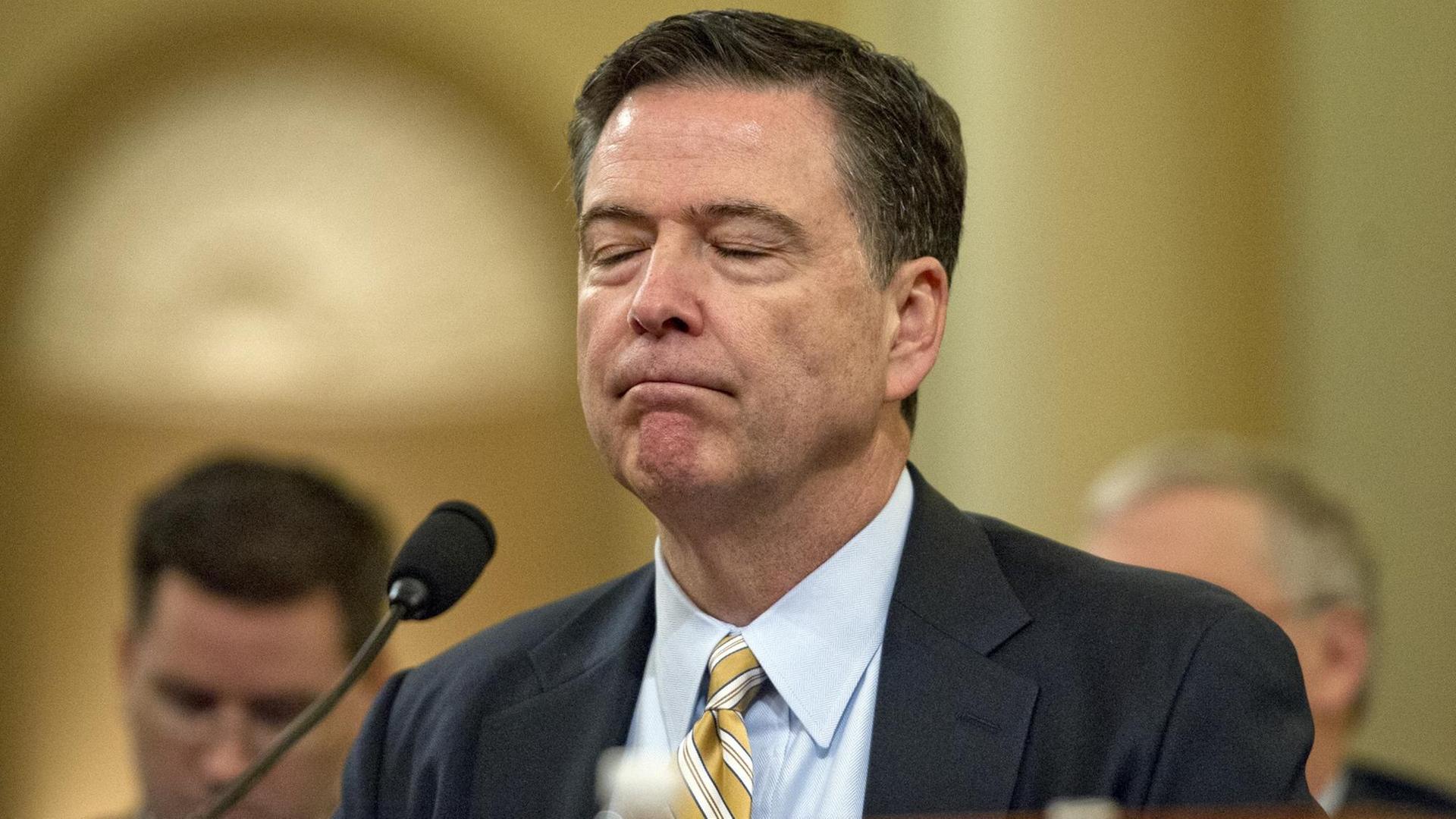 Comey steht mit geschlossenen Augen im Senatsgebäude. Comey steht mit geschlossenen Augen im Senatsgebäude.
