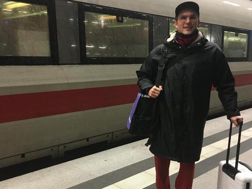 Ein junger Mann - DJ Jakob Mandler - steht vor einem ICE auf dem Bahnsteig. Er hat Gepäck bei sich.