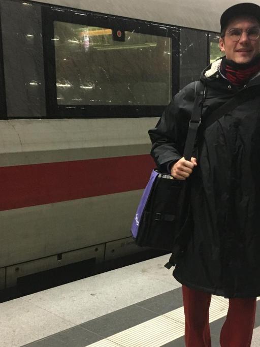 Ein junger Mann - DJ Jakob Mandler - steht vor einem ICE auf dem Bahnsteig. Er hat Gepäck bei sich.