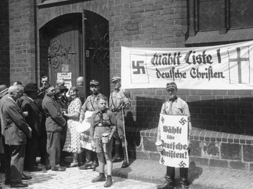 Kirchenwahl in Berlin.- SA-Männer vor Marienkirche mit Plakat "Wählt Liste 1 Deutsche Christen". Hitlerjunge mit Spendendose