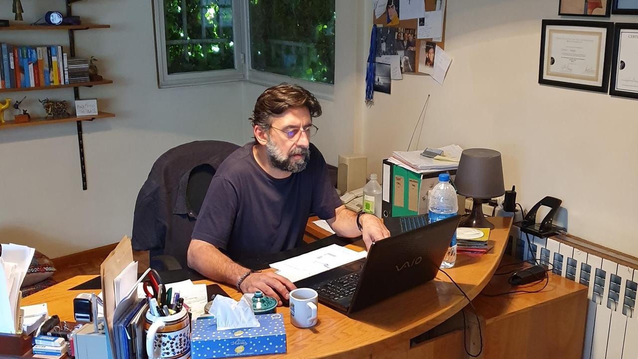 Ramin Sadighi sitzt in seiner Wohnung am Schreibtisch vor seinem Laptop.