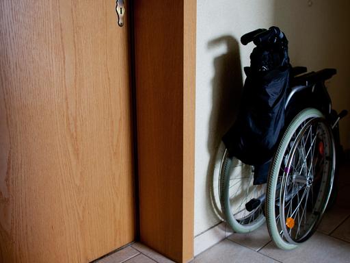 Ein Rollstuhl steht zusammengeklappt in einem Hausflur.