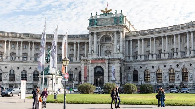 Ein prächtiger klassizistischer Bau, die Wiener Hofburg in Österreich. Ein sommerlicher Tag mit einem Schäfchenwolken und einigen Passanten.