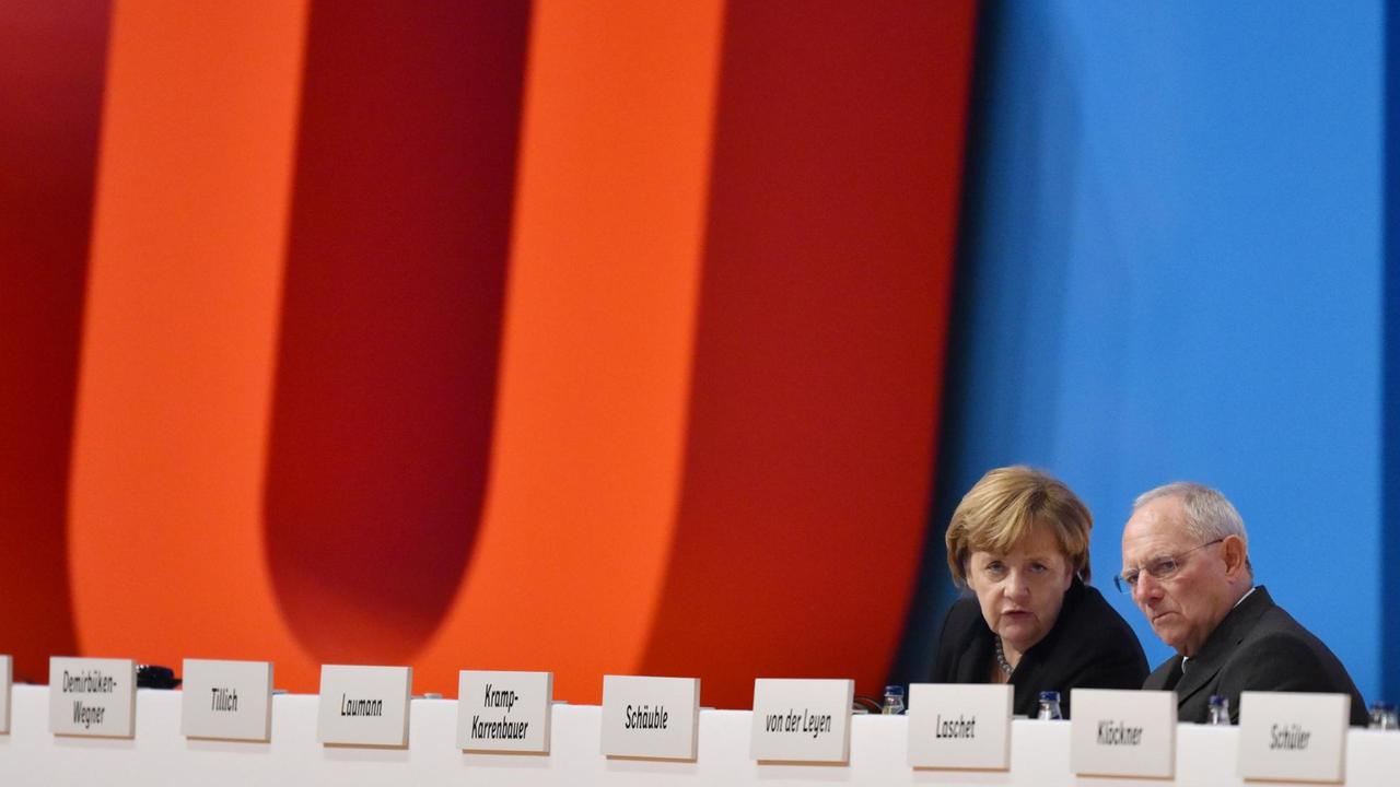 Bundesfinanzminister Wolfgang Schäuble (CDU) sitzt in Karlsruhe (Baden-Württemberg) beim Bundesparteitag neben der CDU-Bundesvorsitzenden und Bundeskanzlerin Angela Merkel. Bundesfinanzminister Wolfgang Schäuble (CDU) sitzt in Karlsruhe (Baden-Württemberg) beim Bundesparteitag neben der CDU-Bundesvorsitzenden und Bundeskanzlerin Angela Merkel.