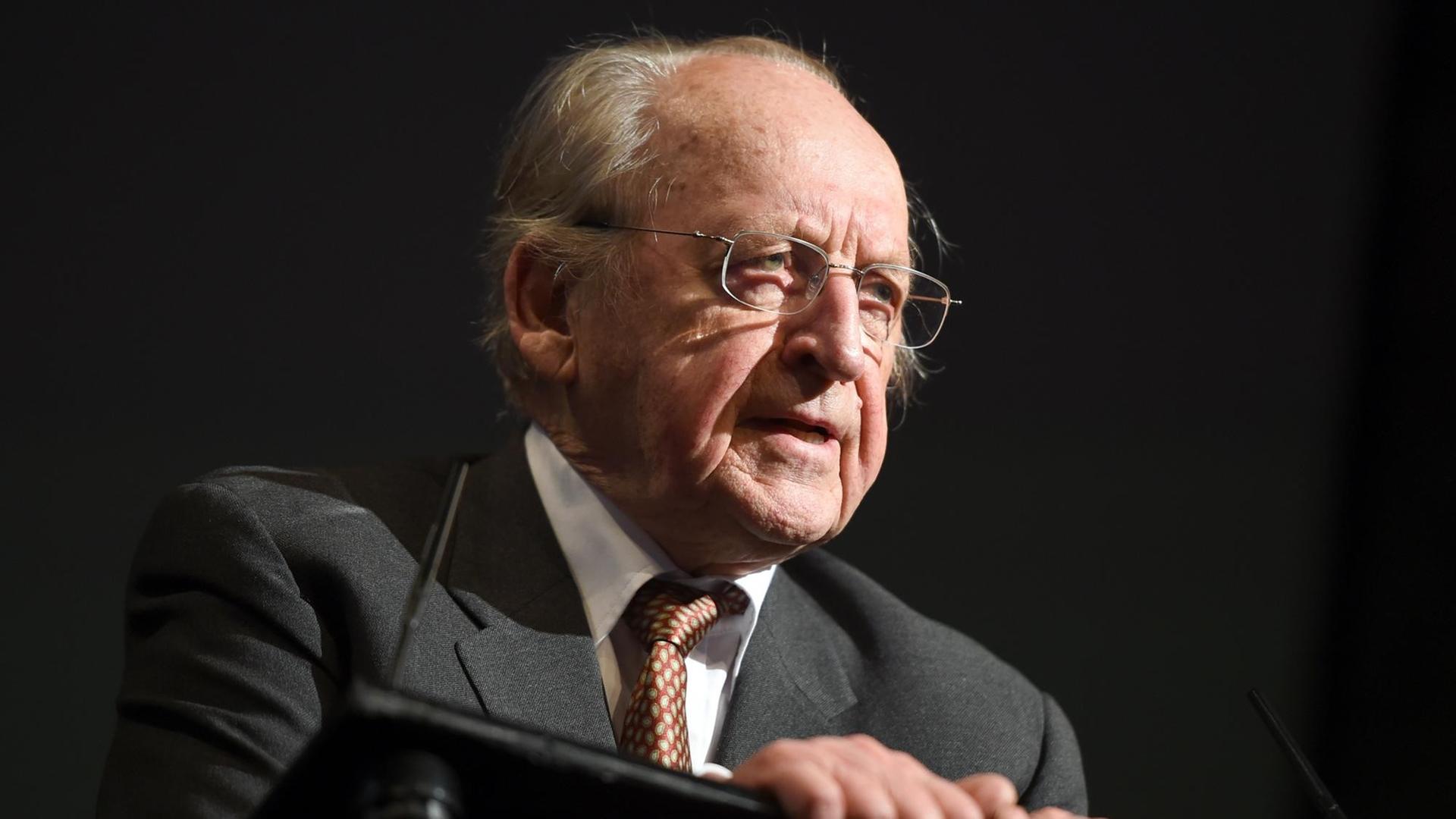 Günther Rühle steht im Dunklen an einem Rednerpult und spricht, nur auf ihm liegt Scheinweiferlicht. Günther Rühle steht im Dunklen an einem Rednerpult und spricht, nur auf ihm liegt Scheinweiferlicht.