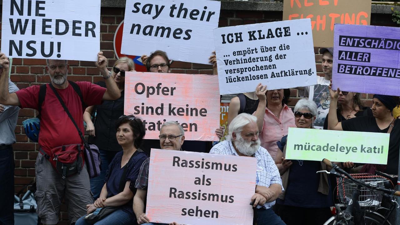 Teilnehmer einer Schweigeminute erinnern mit Plakaten auf der Kölner Keupstrasse am 15. Jahrestag an den NSU-Nagelbombenanschlag Teilnehmer einer Schweigeminute erinnern mit Plakaten auf der Kölner Keupstrasse am 15. Jahrestag an den NSU-Nagelbombenanschlag