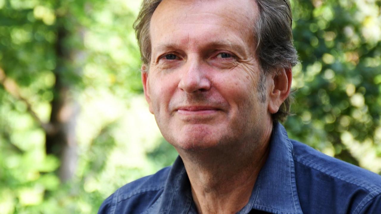 Der Arzt Gerhard Trabert trägt ein blaues Hemd und steht vor Bäumen. Er lächelt in die Kamera. Der Arzt Gerhard Trabert trägt ein blaues Hemd und steht vor Bäumen. Er lächelt in die Kamera.