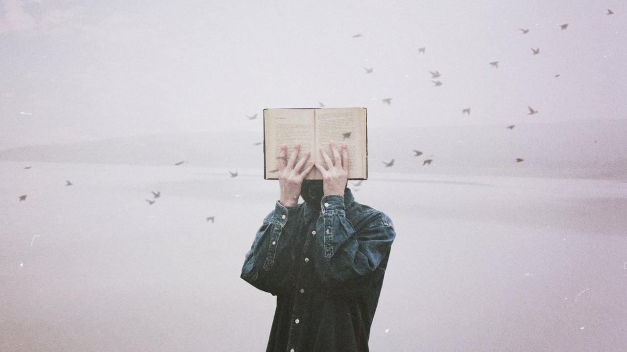 Ein Mann hält sich ein Buch vor sein Gesicht, im Hintergrund fliegt ein Schwarm kleiner Vögel durch das Bild. Ein Mann hält sich ein Buch vor sein Gesicht, im Hintergrund fliegt ein Schwarm kleiner Vögel durch das Bild.