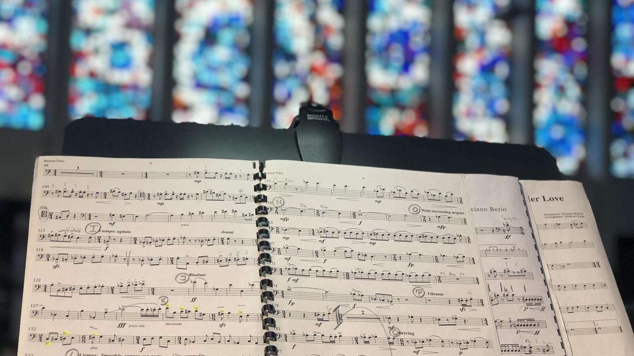 Ein Notenständer mit Notenblättern steht vor den bunten Kirchenfenstern. Ein Notenständer mit Notenblättern steht vor den bunten Kirchenfenstern.