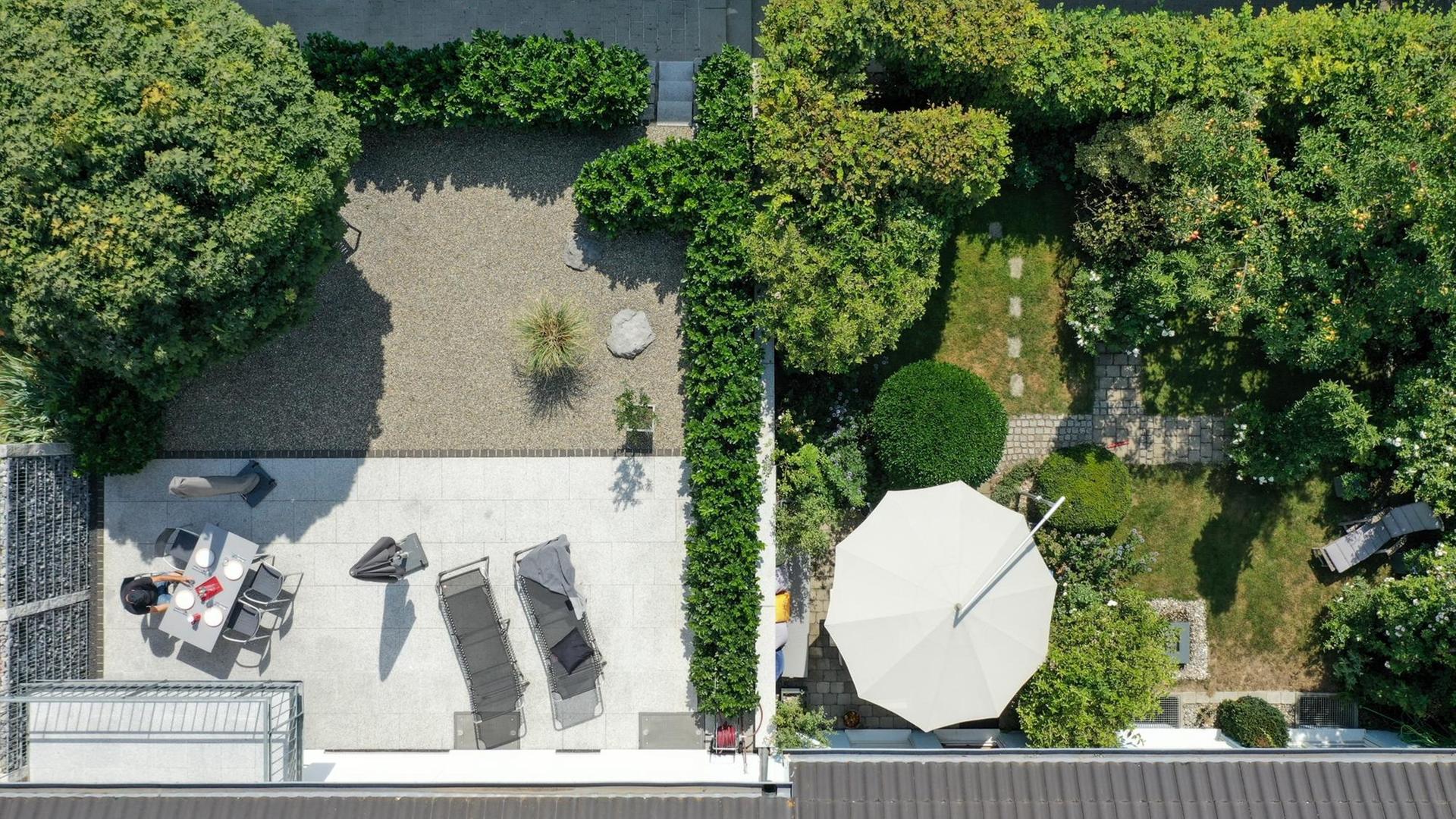 Ein klar strukturierter Steingarten mit wuchtigem Baum und Kirschlorbeerhecke grenzt in einer Reihenhaussiedlung an einen gepflegte grünen Garten mit hoher Hecke, mehreren Bäumen und Essplatz. Der Steingarten ist unterteilt in einen Bereich mit Kiesel und eine Terrasse mit hellem Granit. Ein klar strukturierter Steingarten mit wuchtigem Baum und Kirschlorbeerhecke grenzt in einer Reihenhaussiedlung an einen gepflegte grünen Garten mit hoher Hecke, mehreren Bäumen und Essplatz. Der Steingarten ist unterteilt in einen Bereich mit Kiesel und eine Terrasse mit hellem Granit.