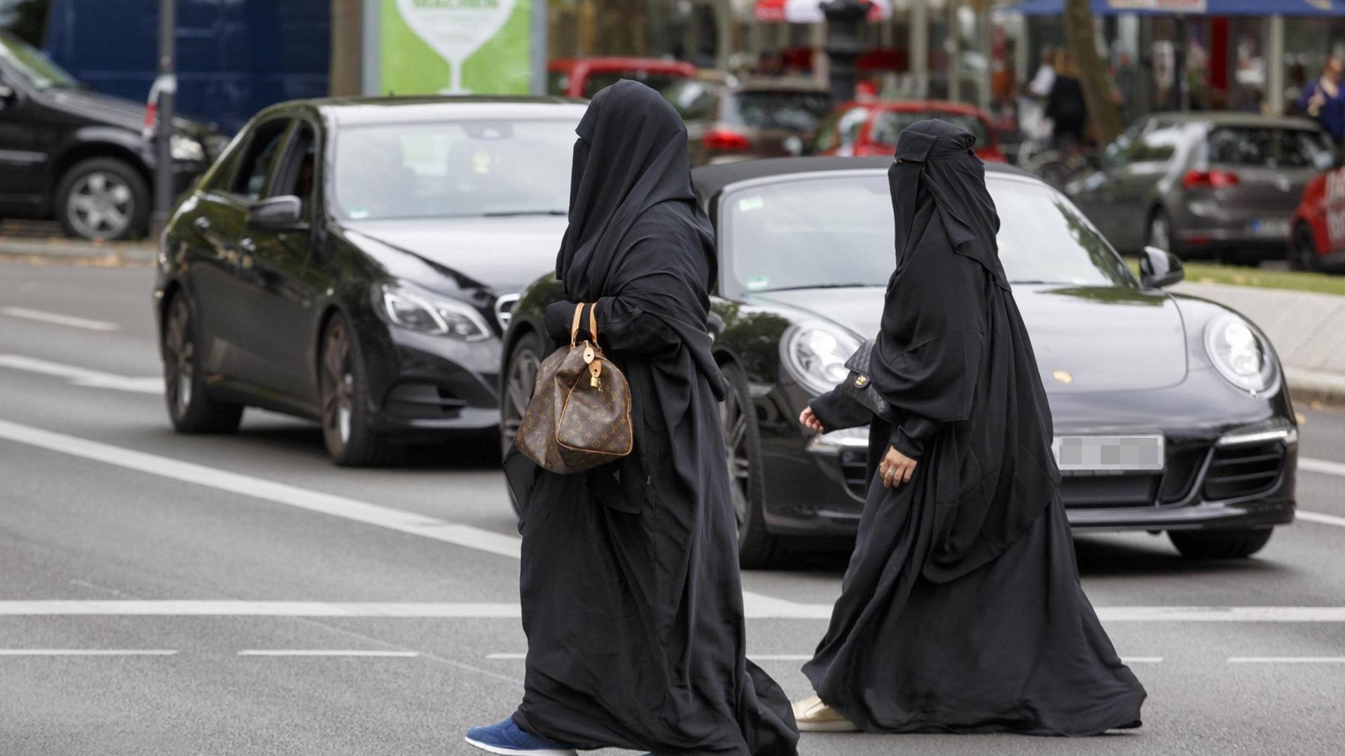 Zwei Frauen überqueren am Berliner Kurfürstendamm die Straße. Sie tragen einen Niqab.