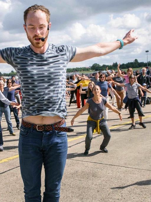 Der Tänzer und Choreograf, Boris Charmatz, Besuchern des "Fous de danse - Ganz Berlin tanzt auf Tempelhof" der Volksbühne auf dem Tempelhofer Feld. 