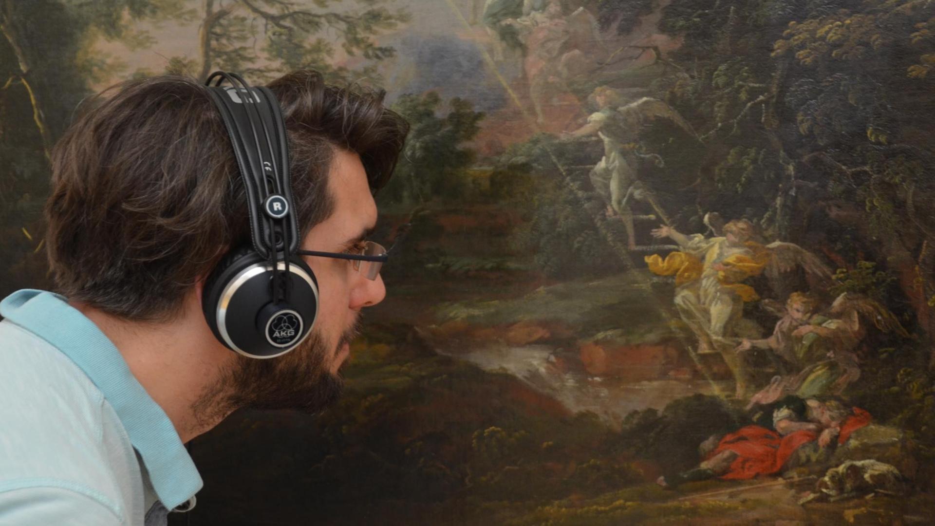 Ein Mann mit Kopfhörern betrachtet Michael Willmanns "Landschaft mit dem Traum Jakobs" (vermutlich 1691) Ein Mann mit Kopfhörern betrachtet Michael Willmanns "Landschaft mit dem Traum Jakobs" (vermutlich 1691)