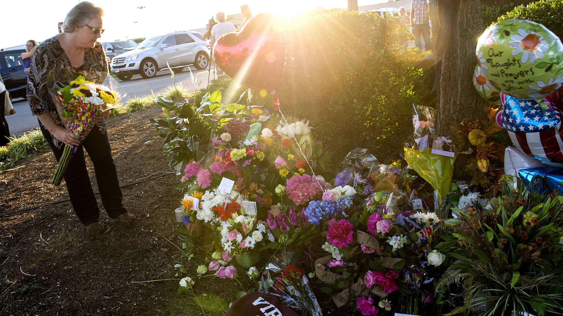 Eine Frau erinnert mit Blumen an die getöteten WDBJ-TV-Mitarbeiter in Roanoke, Virginia. Eine Frau erinnert mit Blumen an die getöteten WDBJ-TV-Mitarbeiter in Roanoke, Virginia.