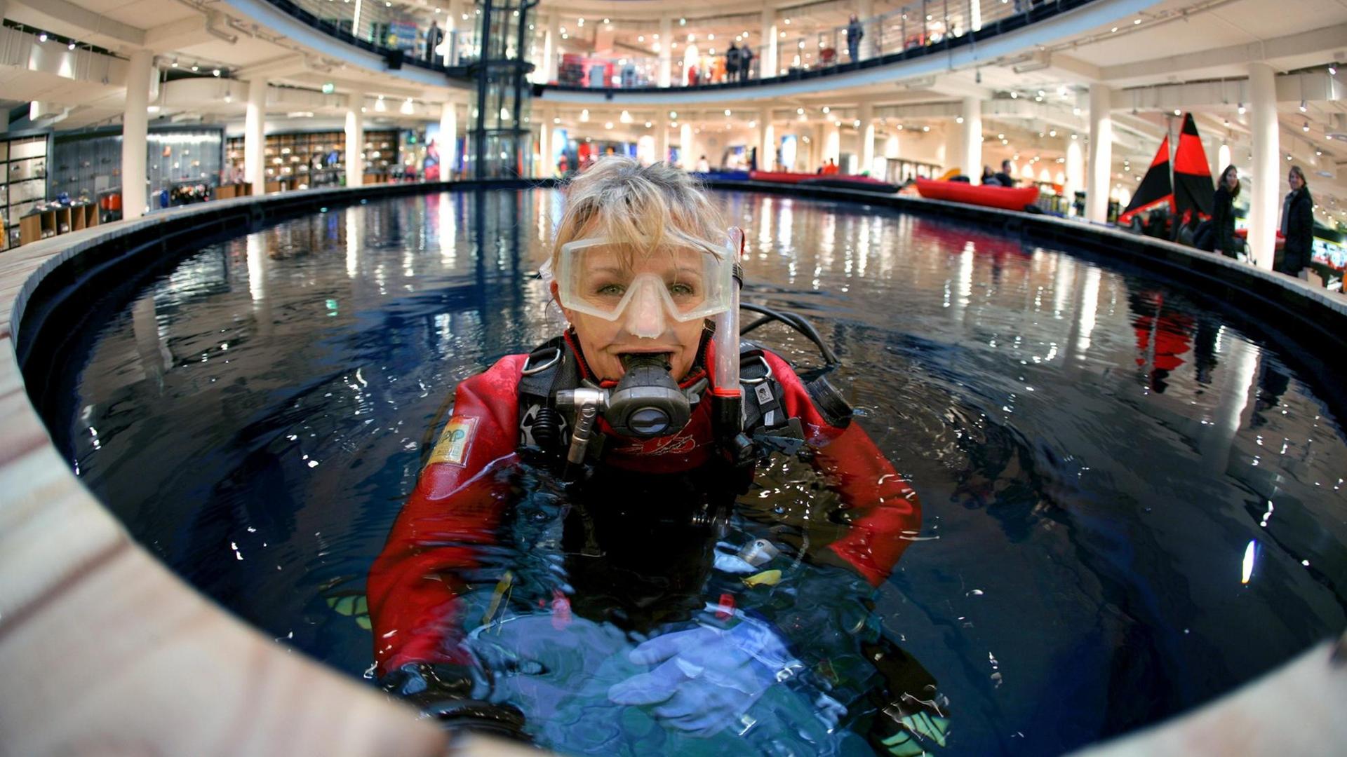 Eine junge Frau mit Taucherausrüstung im Test-Wasserbecken eines Outdoor-Ausrüsters. Eine junge Frau mit Taucherausrüstung im Test-Wasserbecken eines Outdoor-Ausrüsters.