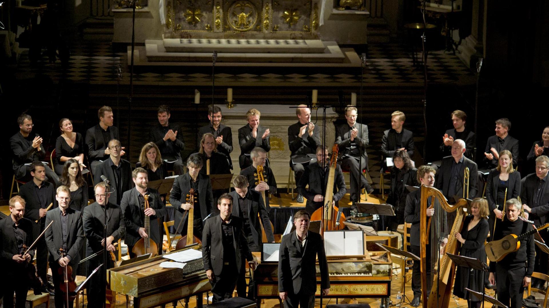 Das Orchester steht mit historischen Instrumenten auf einer Bühne. Das Orchester steht mit historischen Instrumenten auf einer Bühne.
