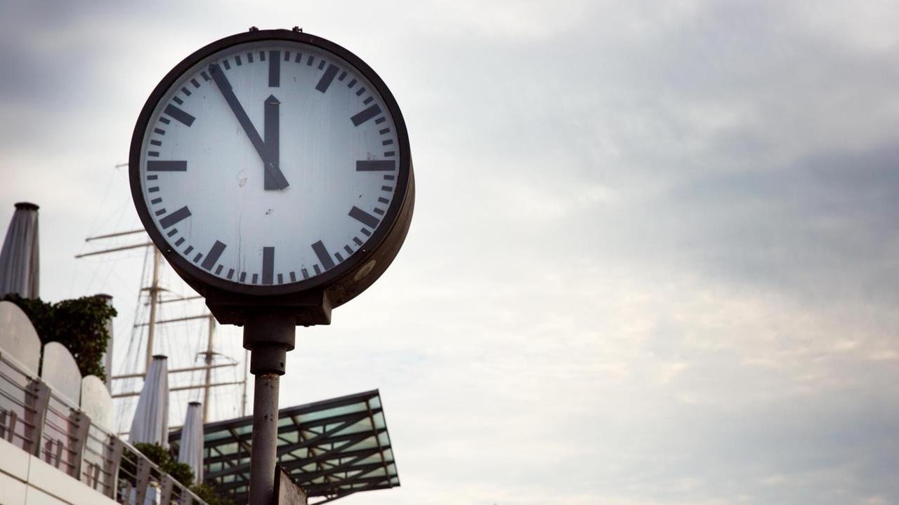 Uhr zeigt 5 vor 12 an. Uhr zeigt 5 vor 12 an.