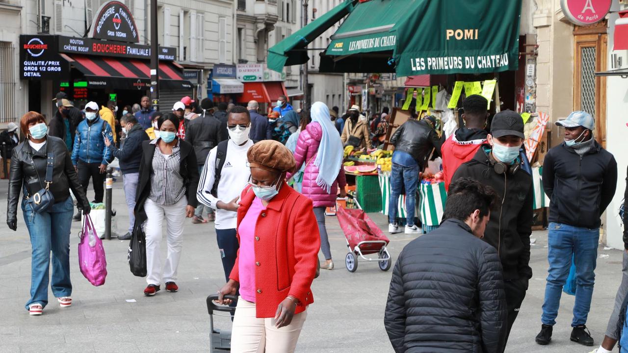 Menschen mit Mund-Nasen-Schutzmasken gehen am 12. Mai 2020 durch das Pariser Viertel Goutte d'Or Menschen mit Mund-Nasen-Schutzmasken gehen am 12. Mai 2020 durch das Pariser Viertel Goutte d'Or