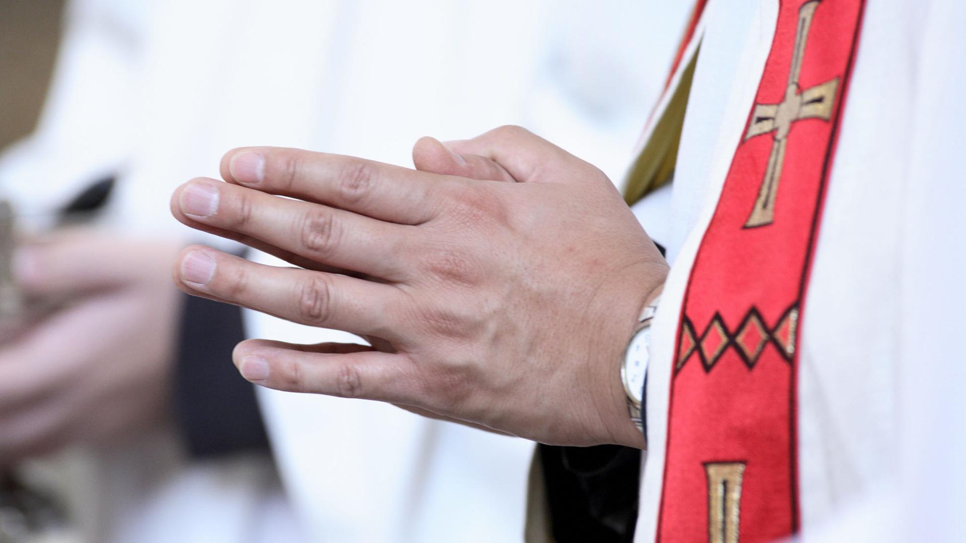 Nahaufnahme betender Hände eines katholischen Priesters während einer Messe Nahaufnahme betender Hände eines katholischen Priesters während einer Messe