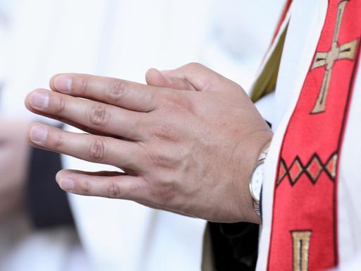 Nahaufnahme betender Hände eines katholischen Priesters während einer Messe