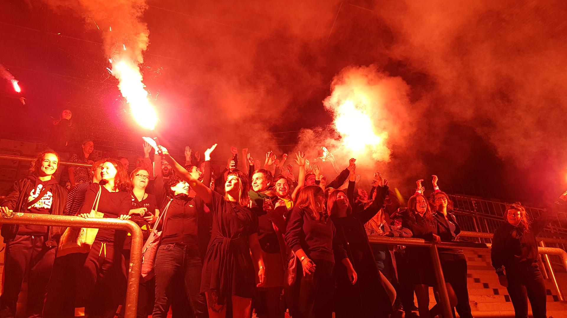 Weibliche Ultrafans aus ganz Europa zur Eröffnung der Ausstellung "Fan.Tastic Females". Eine Gruppe Frauen steht in einem Fußballstadion, das durch Feuer beleuchtet wird. Weibliche Ultrafans aus ganz Europa zur Eröffnung der Ausstellung "Fan.Tastic Females". Eine Gruppe Frauen steht in einem Fußballstadion, das durch Feuer beleuchtet wird.