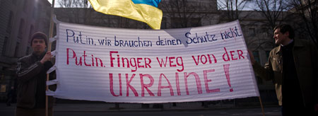 Zwei ukrainische Demonstranten halten in Berlin vor der russischen Botschaft ein Plakat.