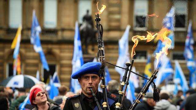 Ein Unabhängigkeitsbefürworter spielt bei einer Demonstration im schottischen Glasgow auf einem Dudelsack, aus dem Flammen hervorsteigen.