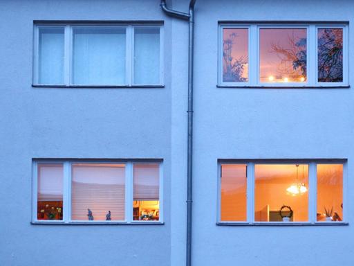 Berlin. In einem Mehrfamilienhaus im Bezirk Steglitz-Zehlendorf sind in der Abenddämmerung bereits einige Fenster erleuchtet.