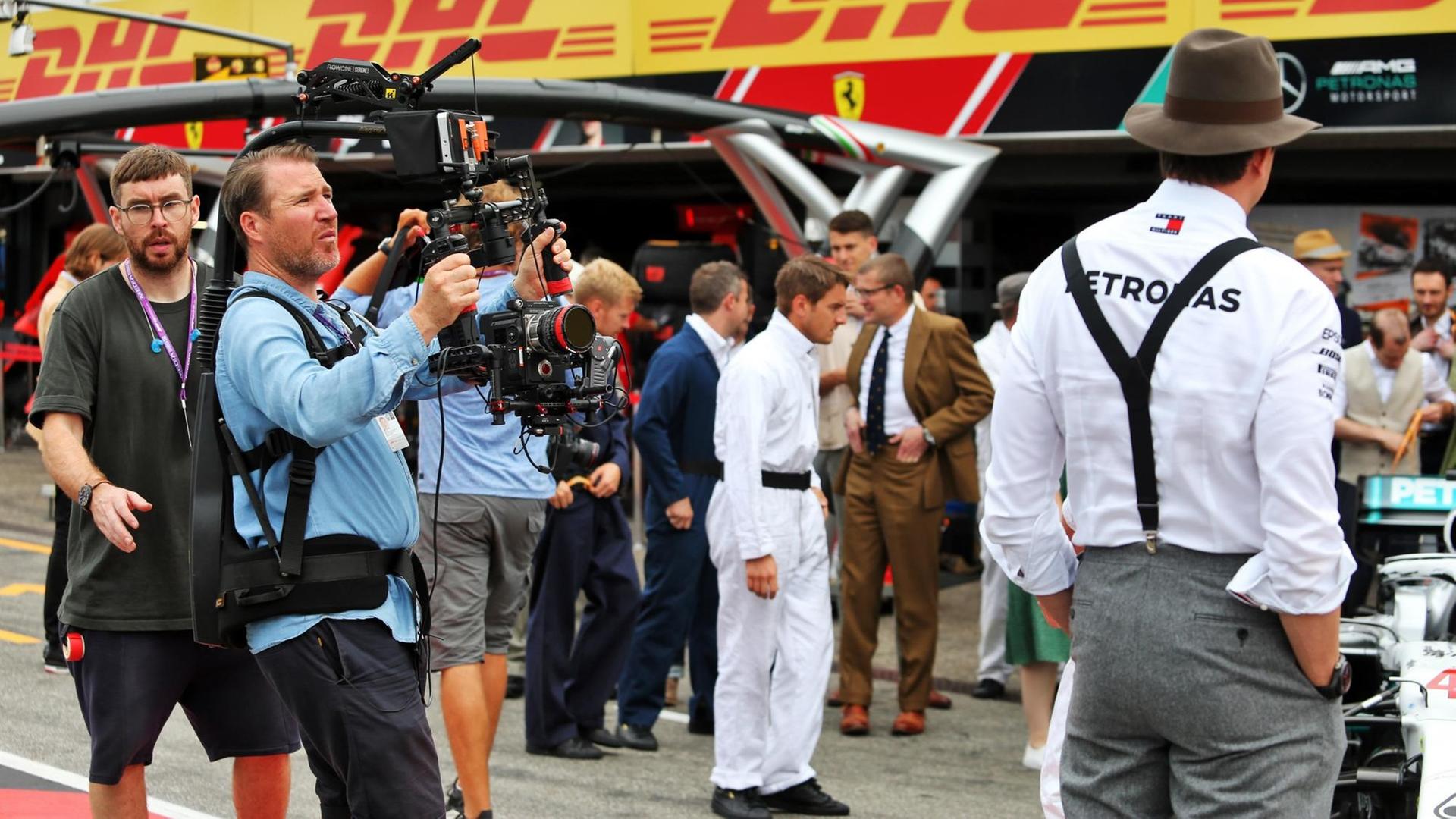 Eine Filmcrew steht vor der Box des Formel1-Teams von Mercedes