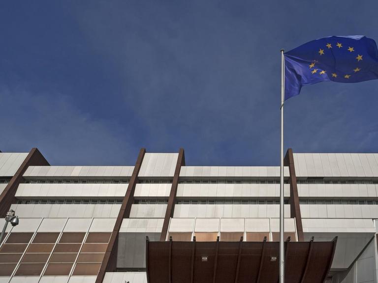 Wehende Europafahne vor dunklem Himmel vor dem Europarat in Straßburg
