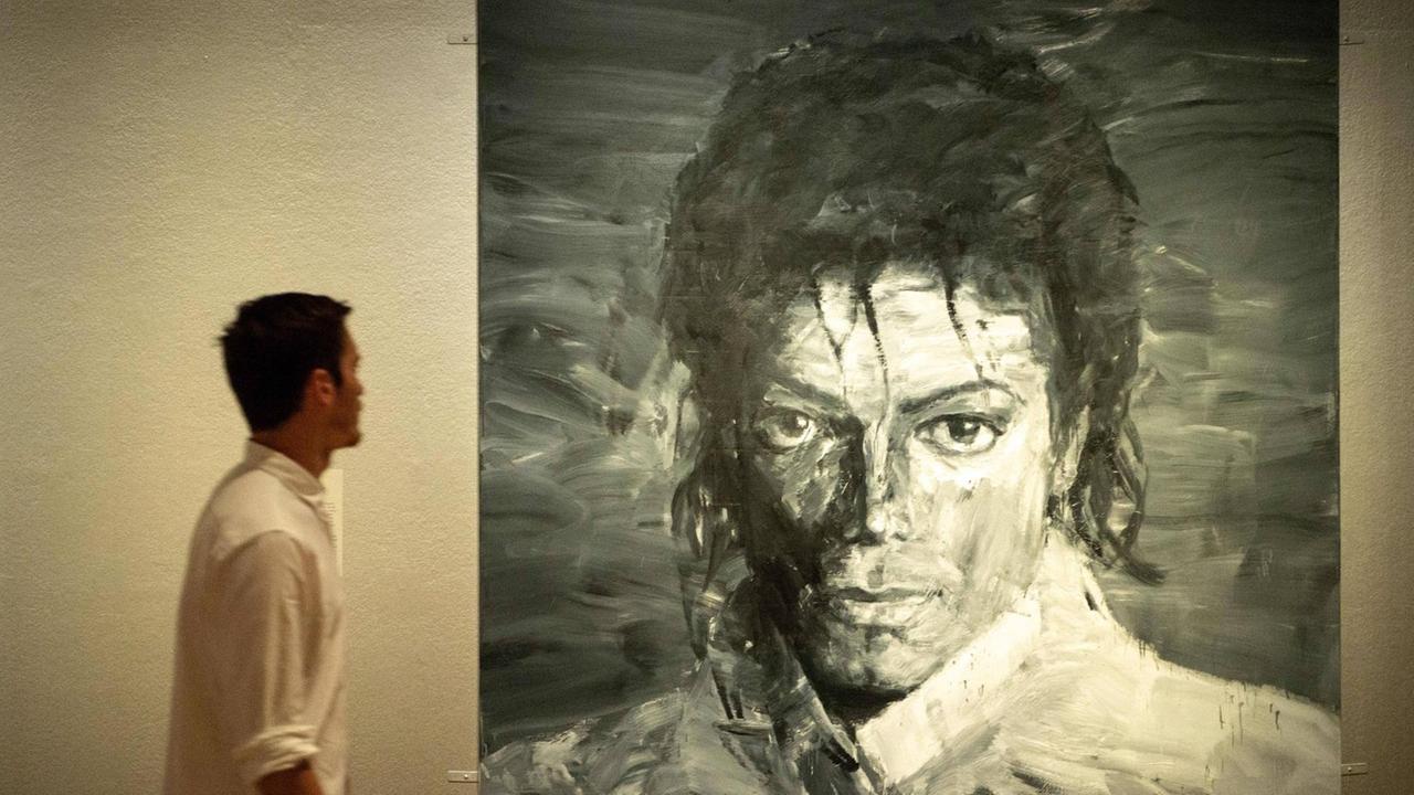 Mann mit weißem Hemd vor Michael Jackson Porträt Mann mit weißem Hemd vor Michael Jackson Porträt