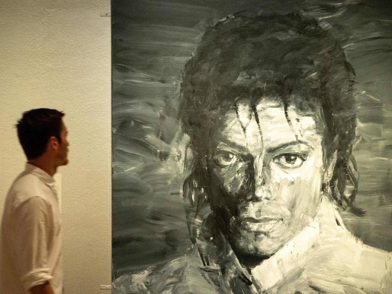 Mann mit weißem Hemd vor Michael Jackson Porträt