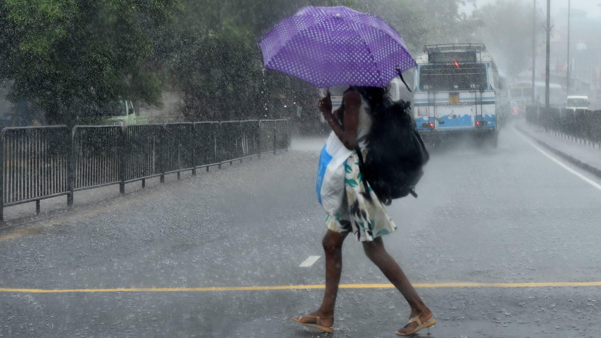 Eine Frau geht in Colombo, Sri Lanka, durch den Regen Eine Frau geht in Colombo, Sri Lanka, durch den Regen