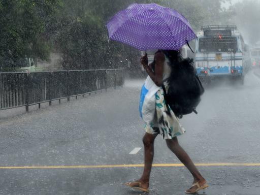 Eine Frau geht in Colombo, Sri Lanka, durch den Regen