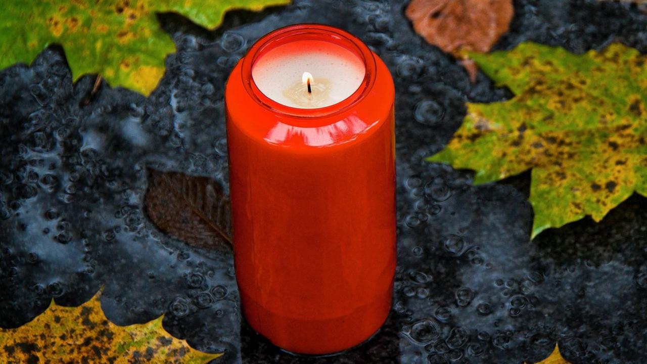 Ein Grablicht zu Allerheiligen im Herbst mit Blättern Ein Grablicht zu Allerheiligen im Herbst mit Blättern