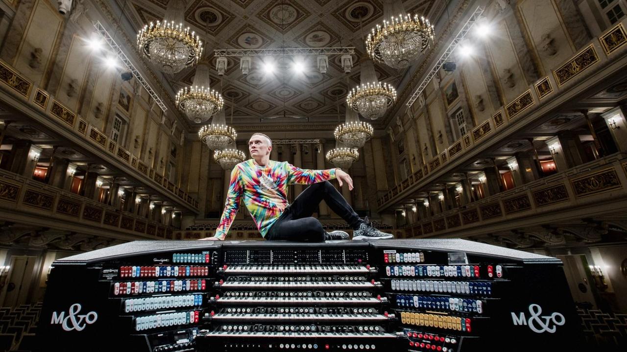 Cameron Carpenter sitzt auf seiner Orgel, im Hintergrund Kronleuchter des Saales Cameron Carpenter sitzt auf seiner Orgel, im Hintergrund Kronleuchter des Saales