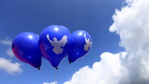 Blaue Luftballons mit dem Symbol einer Friedenstaube schweben am 23.08.2014 in Letzlingen (Sachsen-Anhalt) in der Luft. Eine Woche lang sollen Aktionen des Friedenscamps "War starts here" stattfinden. Foto: Jens Wolf/dpa
