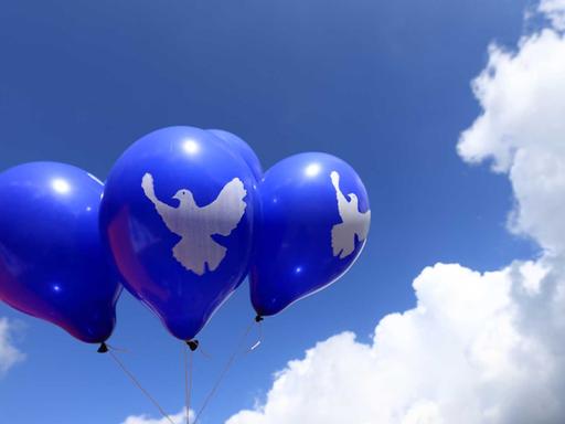 Blaue Luftballons mit dem Symbol einer Friedenstaube schweben am 23.08.2014 in Letzlingen (Sachsen-Anhalt) in der Luft. Eine Woche lang sollen Aktionen des Friedenscamps "War starts here" stattfinden. Foto: Jens Wolf/dpa