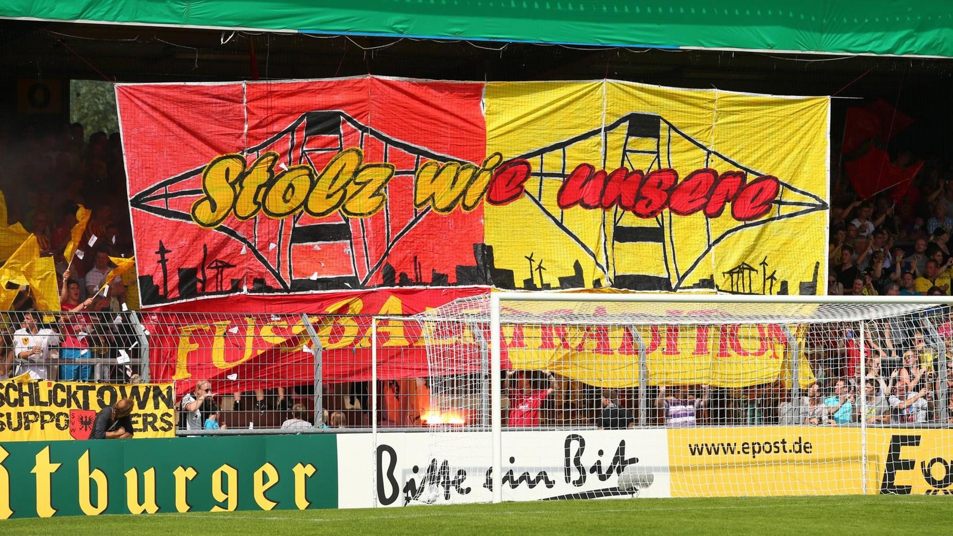 Choreografie der Wilhelmshavener Fans in der Heimkurve. Sie halten ein großes, buntes Banner mit der Aufschrift: "Stolz wie unsere Fußballtradition" hoch. Choreografie der Wilhelmshavener Fans in der Heimkurve. Sie halten ein großes, buntes Banner mit der Aufschrift: "Stolz wie unsere Fußballtradition" hoch.