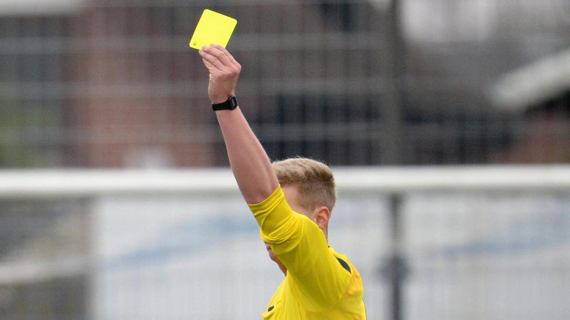 Der Schiedsrichter zeigt bei einem Fußballspiel in der Oberligaeine gelbe Karte