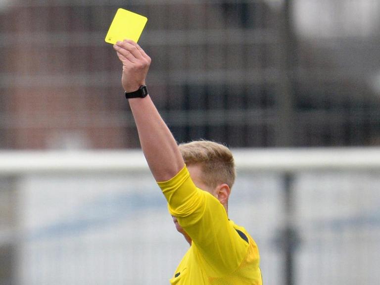 Der Schiedsrichter zeigt bei einem Fußballspiel in der Oberligaeine gelbe Karte