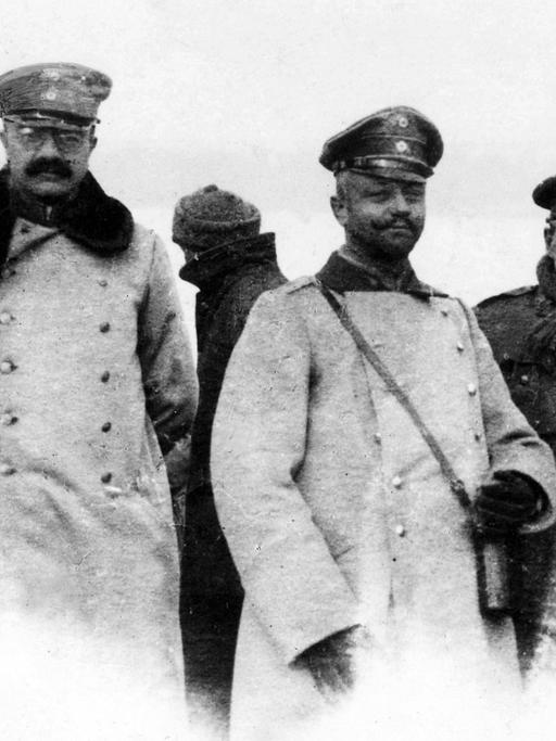 Schwarz-weiß-Foto deutscher und britischer Offiziere im Niemandsland während des inoffiziellen Waffenstillstands an Weihnachten 1914 im Ersten Weltkrieg. Sie stehen nebeneinander und schauen in die Kamera.