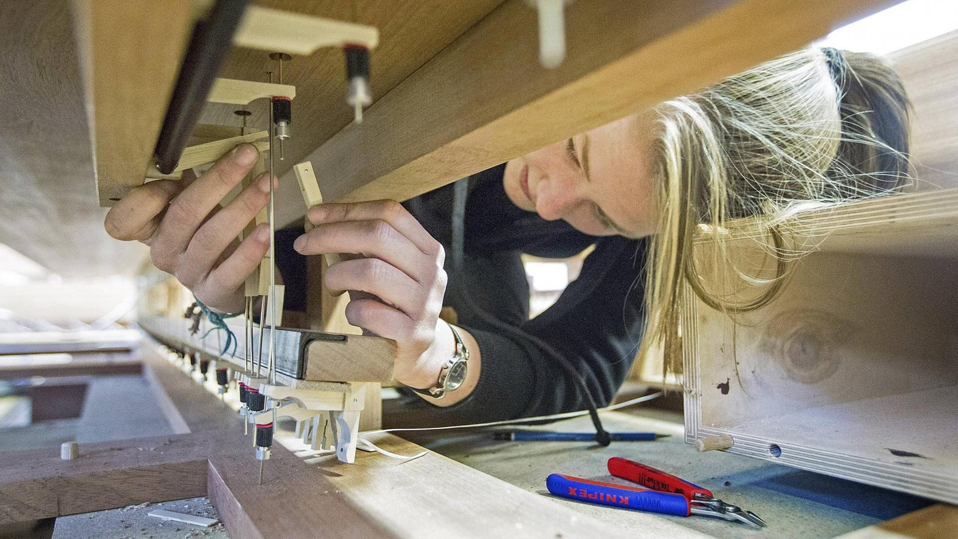 Eine junge Frau arbeitet an einem Orgel-Spieltisch in einer Orgelwerkstatt. Eine junge Frau arbeitet an einem Orgel-Spieltisch in einer Orgelwerkstatt.