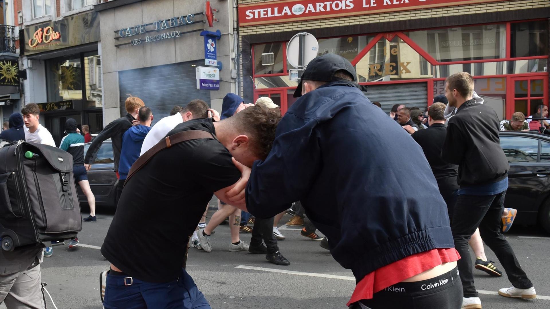 Zwei Fußballfans ringen miteinander, im Hintergrund weitere Krawalle Zwei Fußballfans ringen miteinander, im Hintergrund weitere Krawalle