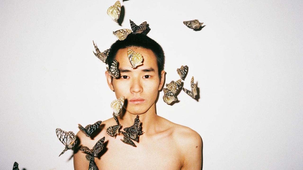 Ein Mann umgeben von einem Schwarm Schmetterlingen, fotografiert von Ren Hang. Ein Mann umgeben von einem Schwarm Schmetterlingen, fotografiert von Ren Hang.