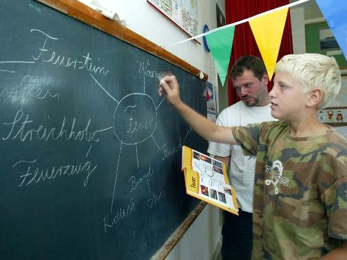 Ein Schüler schreibt an eine Tafel Ein Schüler schreibt an eine Tafel