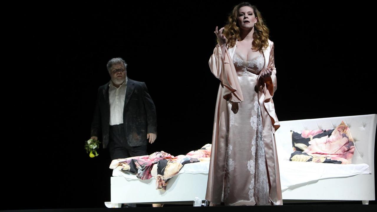 Giselle steht im Nachthemd vor einem zerwühlten Bett, im Hintergrund taucht ihr Mann auf. Giselle steht im Nachthemd vor einem zerwühlten Bett, im Hintergrund taucht ihr Mann auf.