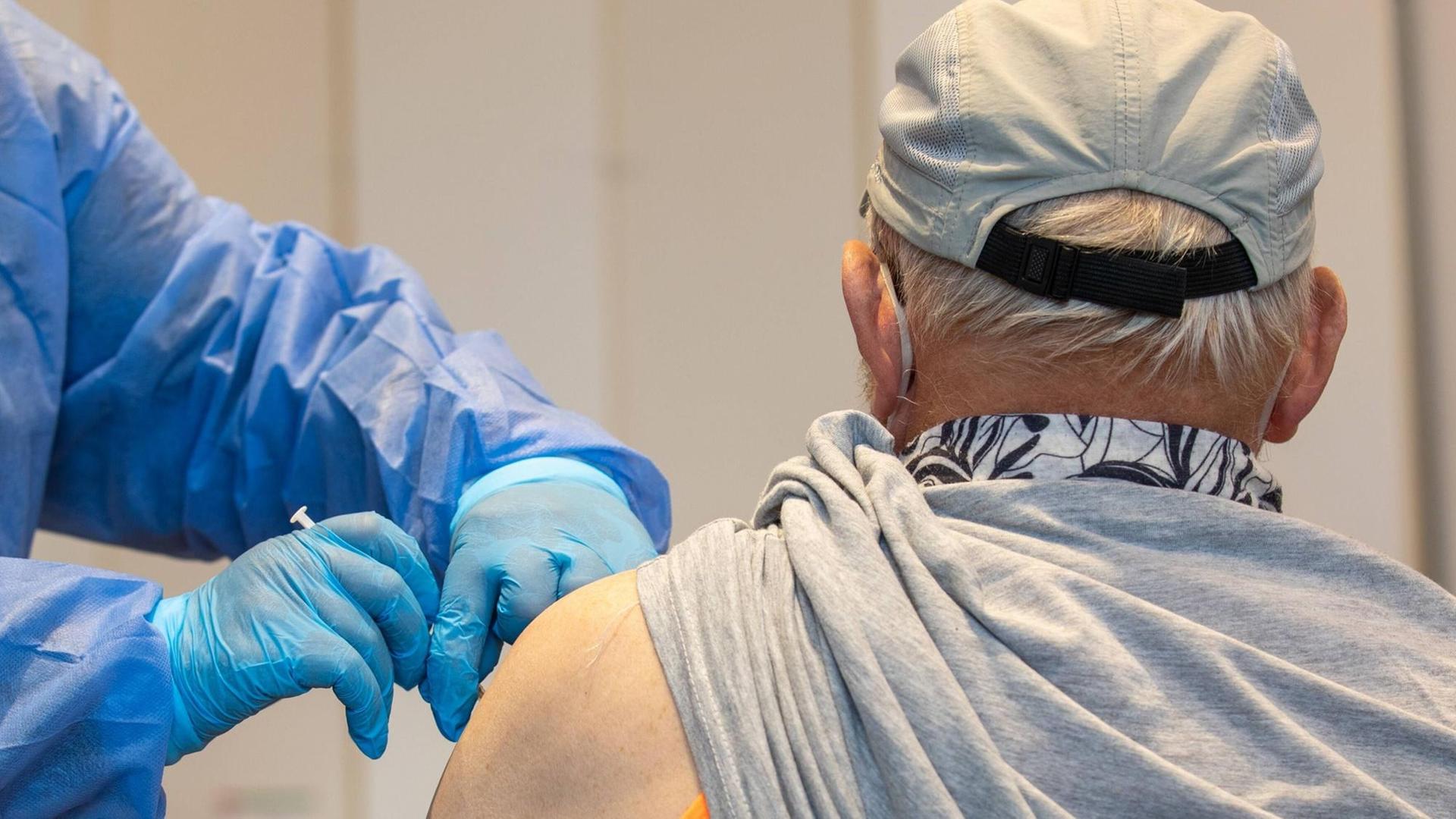 Eine Krankenschwester von einem mobilen Impfteam impft einen älteren Mann in einer Sporthalle im sächsischen Pirna. Eine Krankenschwester von einem mobilen Impfteam impft einen älteren Mann in einer Sporthalle im sächsischen Pirna.