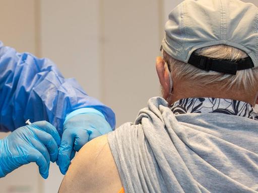 Eine Krankenschwester von einem mobilen Impfteam impft einen älteren Mann in einer Sporthalle im sächsischen Pirna.