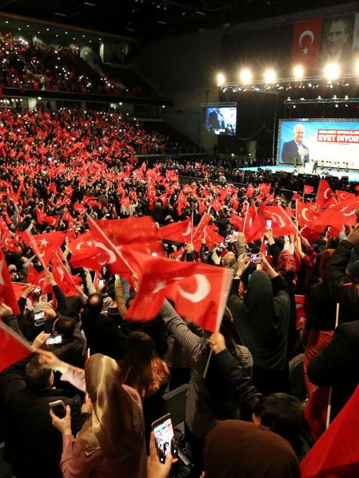 Teilnehmer bei einer Veranstaltung mit dem türkischen Ministerpräsidenten Yildirim in Oberhausen halten türkische Fahnen in den Händen.